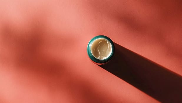 Jar of face cream on a red background with sunlight casting a shadow, creating a bold and vibrant look. Perfect for luxury beauty products. Elegant packaging promotes wellness and self care