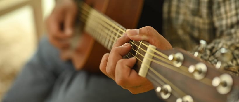 Close up shot of man playing an acoustic guitar. Relaxation, hobbies, and creativity concept.