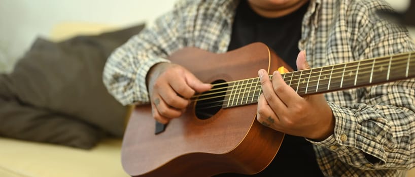 Close up shot of man playing an acoustic guitar. Relaxation, hobbies, and creativity concept.