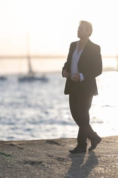 Businessman is walking on a pier at sunset, enjoying the view of the water and the boats