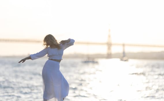 Woman is gracefully dancing on the beach, silhouetted by the setting sun, with the golden gate bridge in the distance