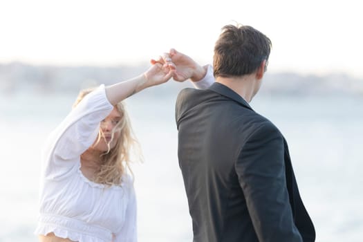 Man and a woman are dancing by the water on a windy day