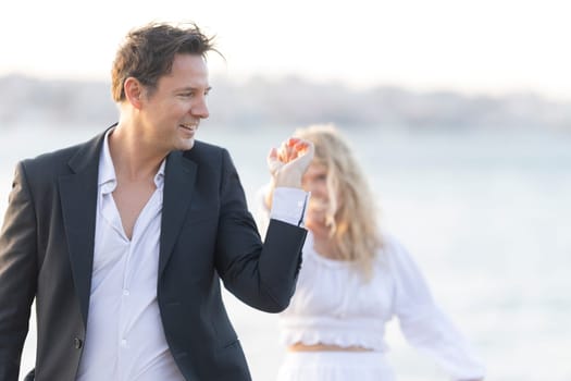 Elegant couple is dancing by the sea, enjoying the romantic atmosphere of the sunset