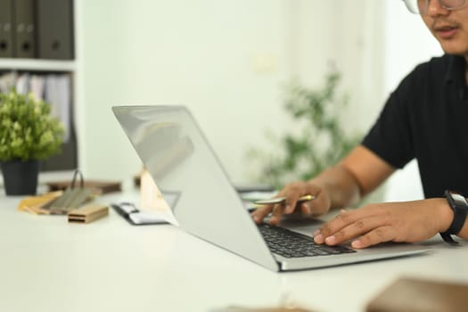 An architect or design professional typing on laptop working on a design project in a modern office.