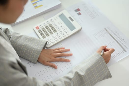 Close up businesswoman working on financial documents, budgeting or financial analysis at desk.