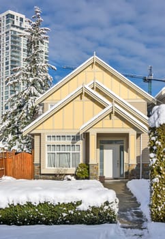 A perfect neighbourhood. Modern high-rise and private residential house in snow on winter season in British Columbia, Canada.