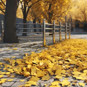 Close-up view of fallen autumn leaves on the ground, with a tree trunk and a metal fence in the background. The leaves are a vibrant shade of yellow, creating a beautiful scene of fall colors.