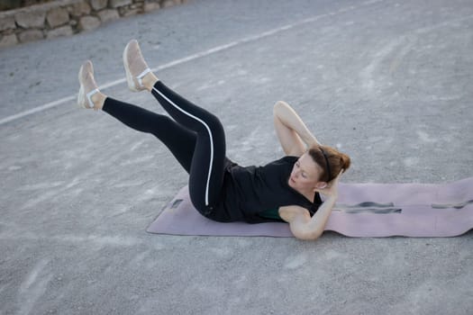 Woman is strengthening her abdominal muscles by doing sit ups on a fitness mat
