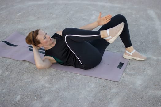 Woman is training her abdominal muscles by doing crunches on a mat
