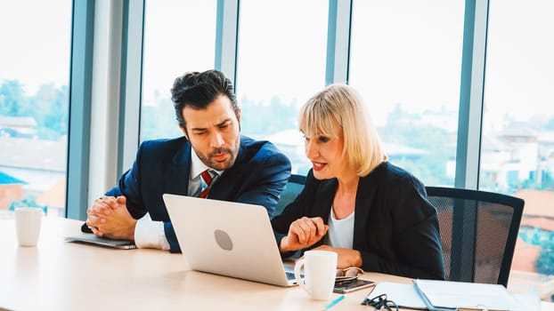 Two business people talk project strategy at office meeting room. Businessman discuss project planning with colleague at modern workplace while having conversation and advice on financial report. Jivy