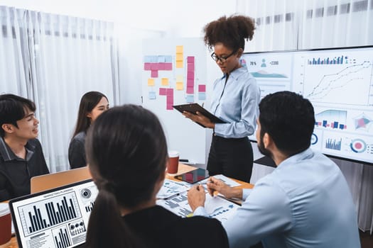 Young african businesswoman presenting data analysis dashboard on TV screen in modern meeting. Business presentation with group of business people in conference room. Concord