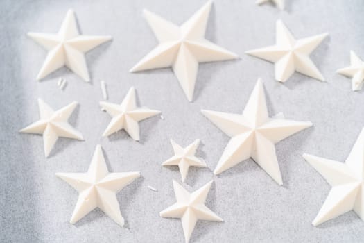 Filling silicone mold with white melted chocolate to make chocolate chocolate stars for American flag mini cupcakes.