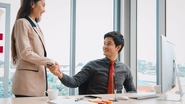 Two business people talk project strategy at office meeting room. Businessman discuss project planning with colleague at modern workplace while having conversation and advice on financial report. Jivy