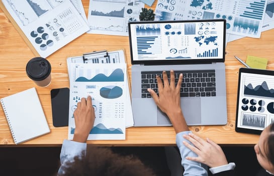 Multiracial analyst team use BI Fintech software to analyze financial data on meeting. Top view finance dashboard data display on laptop screen with analyzed chart for marketing indication. Concord