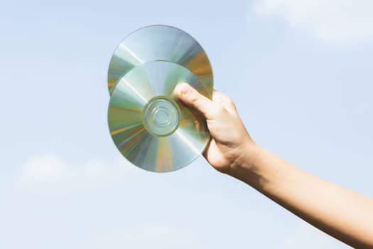 Recyclable CD disk or electric waste held in hand up on sky background. Hand holding electronic trash for recycle reduce and reuse concept to promote clean environment with recycling management. Gyre