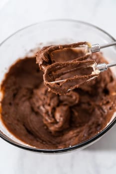 Mixing ingredients in a large glass mixing bowl to bake red velvet bundt cake with cream cheese glaze.