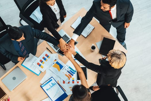 Happy business people celebrate teamwork success together with joy at office table shot from top view . Young businessman and businesswoman workers express cheerful victory show unity support . Jivy