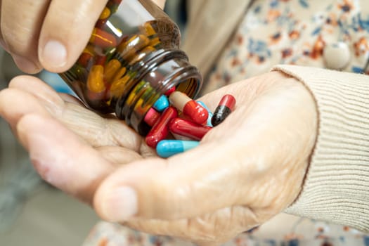 Asian senior woman patient holding antibiotics capsule pills  for treatment infection patient in hospital, Pharmacy drugstore concept.