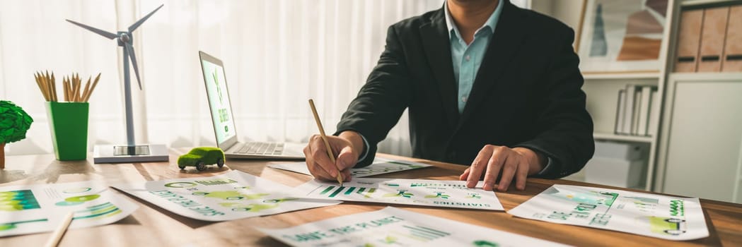 Businessman planning for green business strategy in office with paper documents focused on eco-friendly and energy sustainable policy to reduce CO2 emission for green environment. Trailblazing