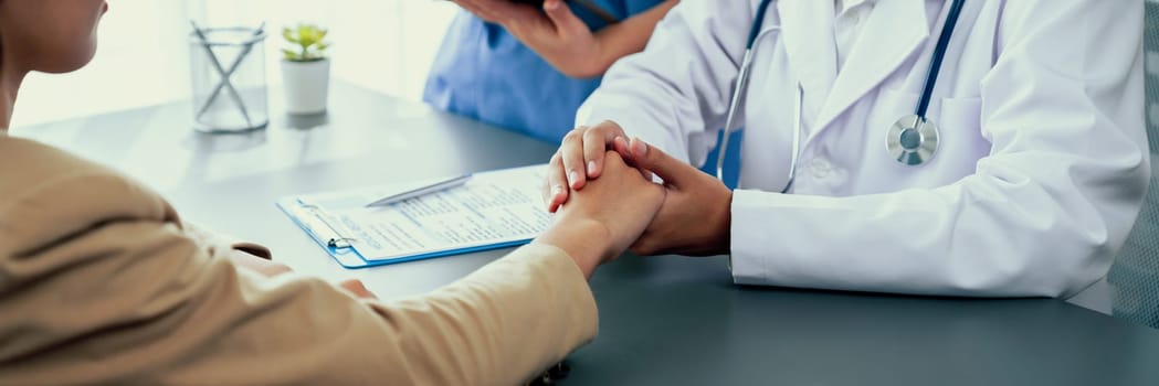 Doctor show medical diagnosis report and providing compassionate healthcare consultation while holding young patient hand for being supportive and professional in doctor clinic office. Neoteric