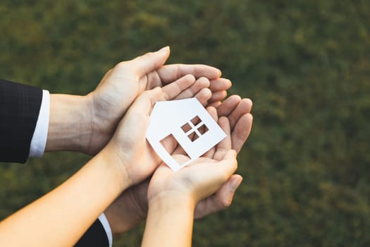 Businessman hold house icon together with child's hand, presenting house loan opportunity as part of real estate sales. Promoting eco-smart homes, embodying vision for sustainable future. Gyre