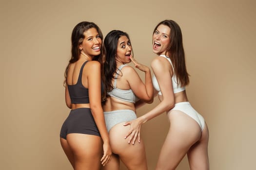 Laughing millennial different women in underwear with open mouth have fun, enjoy beauty care, isolated on beige background, studio. Self love, wellness and anti cellulite treatment, surgery