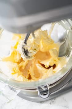 Whisking buttercream frosting in a glass mixing bowl with an electric kitchen mixer for American flag mini cupcakes.