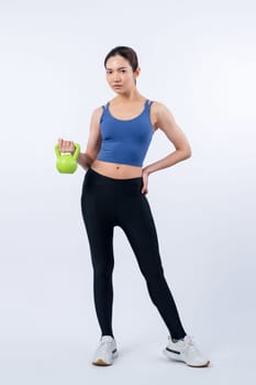 Vigorous energetic woman doing kettlebell weight lifting exercise on isolated background. Young athletic asian woman strength and endurance training session as body workout routine.