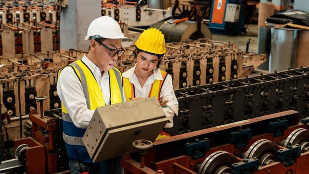 Factory engineer manager with assistant conduct inspection of industrial steel forming machine, exemplifying leadership as metalwork machinery engineering inspection supervisor in the facility.