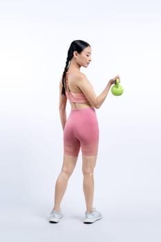 Vigorous energetic woman doing kettlebell weight lifting exercise on isolated background. Young athletic asian woman strength and endurance training session as body workout routine.