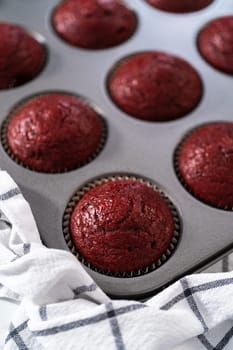 Cooling freshly baked red velvet cupcakes on a kitchen counter.