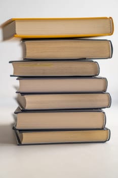 Stack of books on a white background. One book is yellow. Book reading and learning concept.