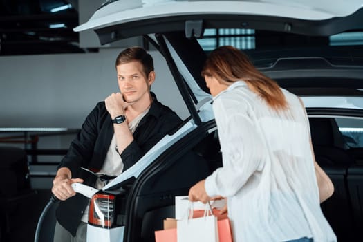 Young woman travel with EV electric car to shopping center parking lot charging in downtown city showing urban sustainability lifestyle by green clean rechargeable energy of electric vehicle innards