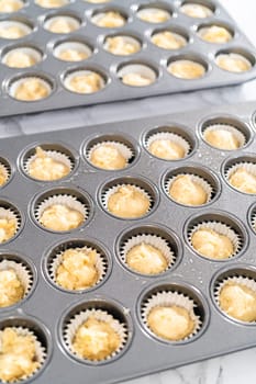 Scooping cupcake batter with dough scoop into a baking pan with liners to bake American flag mini cupcakes.