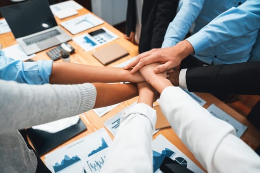 Multiracial business people make synergy hand stack together in meeting room as cooperation or team building for corporate employee in workplace. Meticulous