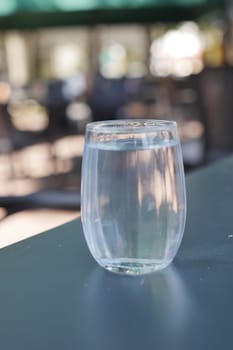 glass of water on table on blur cafe background .