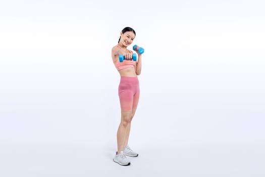 Vigorous energetic woman doing dumbbell weight lifting exercise on isolated background. Young athletic asian woman strength and endurance training session as body workout routine.