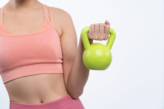 Vigorous energetic woman doing kettlebell weight lifting exercise on isolated background. Young athletic asian woman strength and endurance training session as body workout routine.