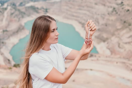 Side view a Young beautiful sensual woman in a mint long dress posing on a volcanic rock high above the sea during sunset. Girl on the nature on overcast sky background. Fashion photo