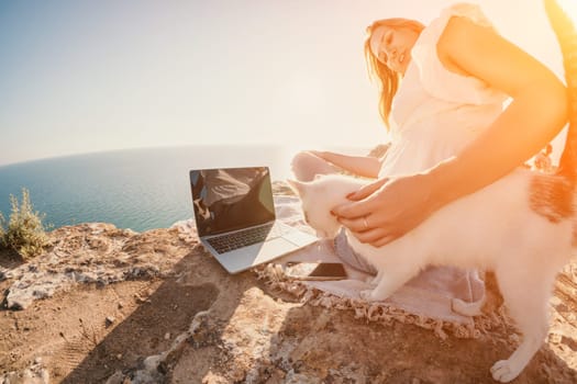 Woman sea laptop. Business woman in yellow hat working on laptop by sea. Close up on hands of pretty lady typing on computer outdoors summer day. Freelance, digital nomad, travel and holidays concept.