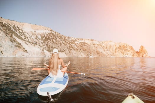 Close up shot of beautiful young caucasian woman with black hair and freckles looking at camera and smiling. Cute woman portrait in a pink bikini posing on a volcanic rock high above the sea