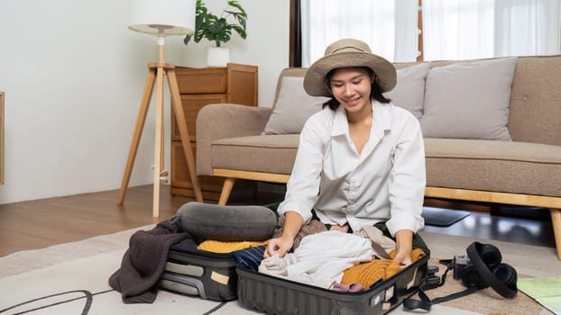 Young woman sit in floor and preparation suitcase for weekend trip. travel concept.