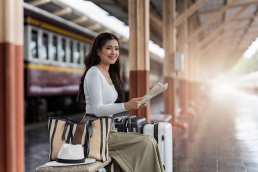 Young woman female traveler looking on map while waiting for the train at train station.