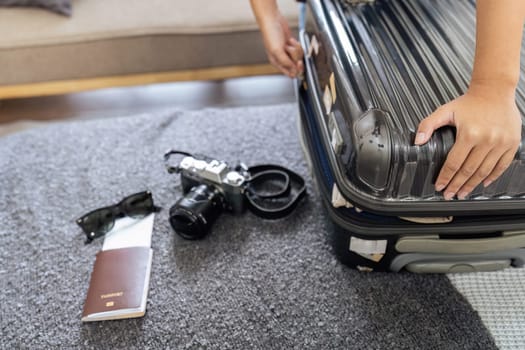 Young woman sit in floor and preparation suitcase for travelling at weekend trip.