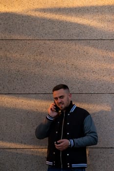 Bearded man using smartphone outdoors at sunset