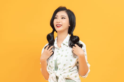 Portrait of attractive young asian woman in pigtails playing with her hair.