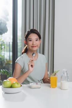 Young woman in fitness clothes having healthy breakfast at home