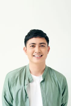 Positive young asian male looking away with smile while standing against white background