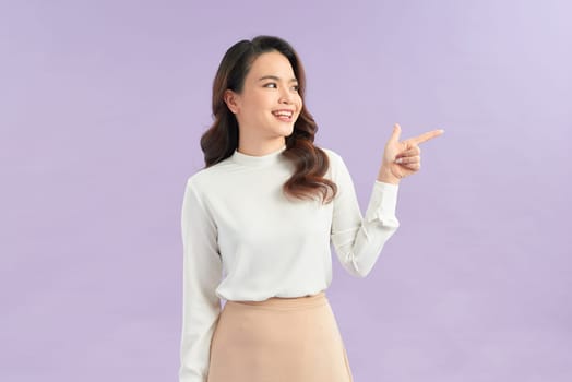 Asian young woman standing makes gesture fingers point upwards above presenting product something