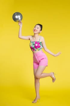 Full length portrait of happy pretty woman with silver balloon in hands on yellow background. Party concept